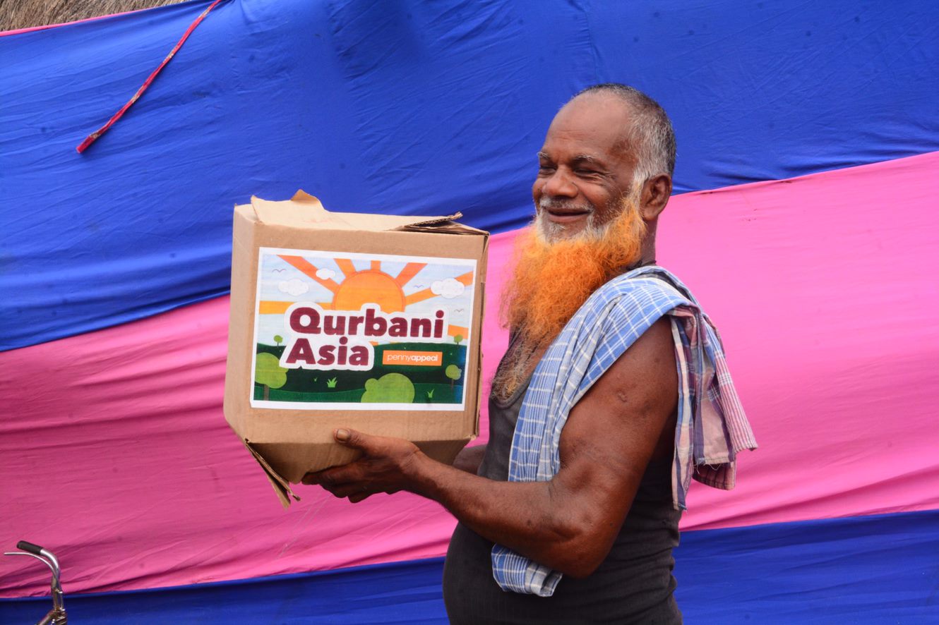 Man with an orange beard holding a Qurbani box
