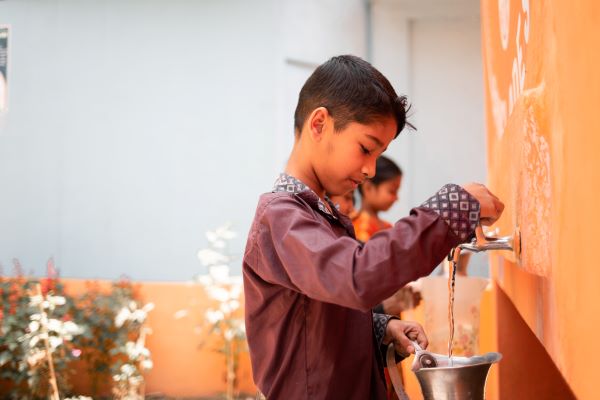 Boy filling up jug from a tap