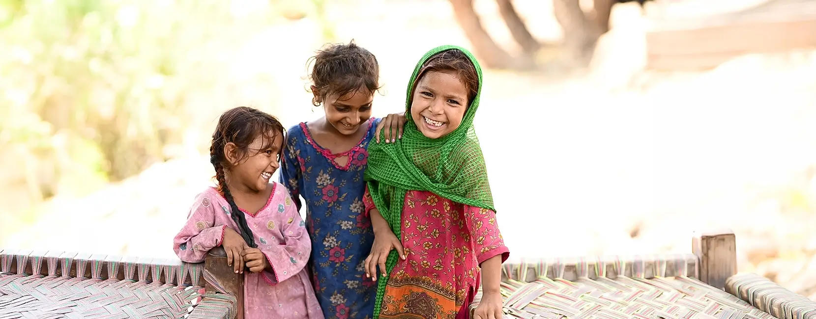 Three young girls laugh and smile together.