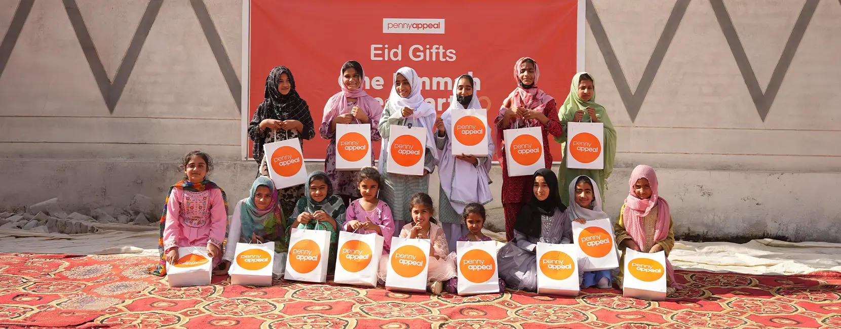 A group of smiling children holding bags of Eid gifts from Penny Appeal donors.