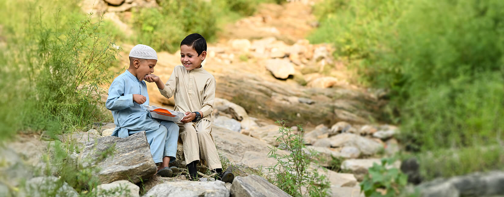 Two boys sharing a meal outdoors through Penny Appeal’s Feed Our World program.