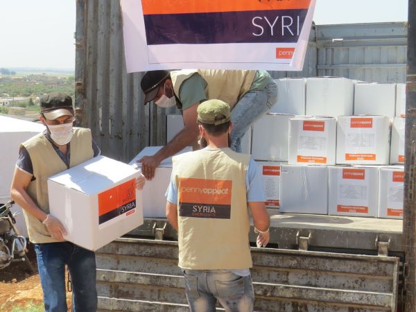 Men unloading penny appeal boxes off a truck wearing face masks
