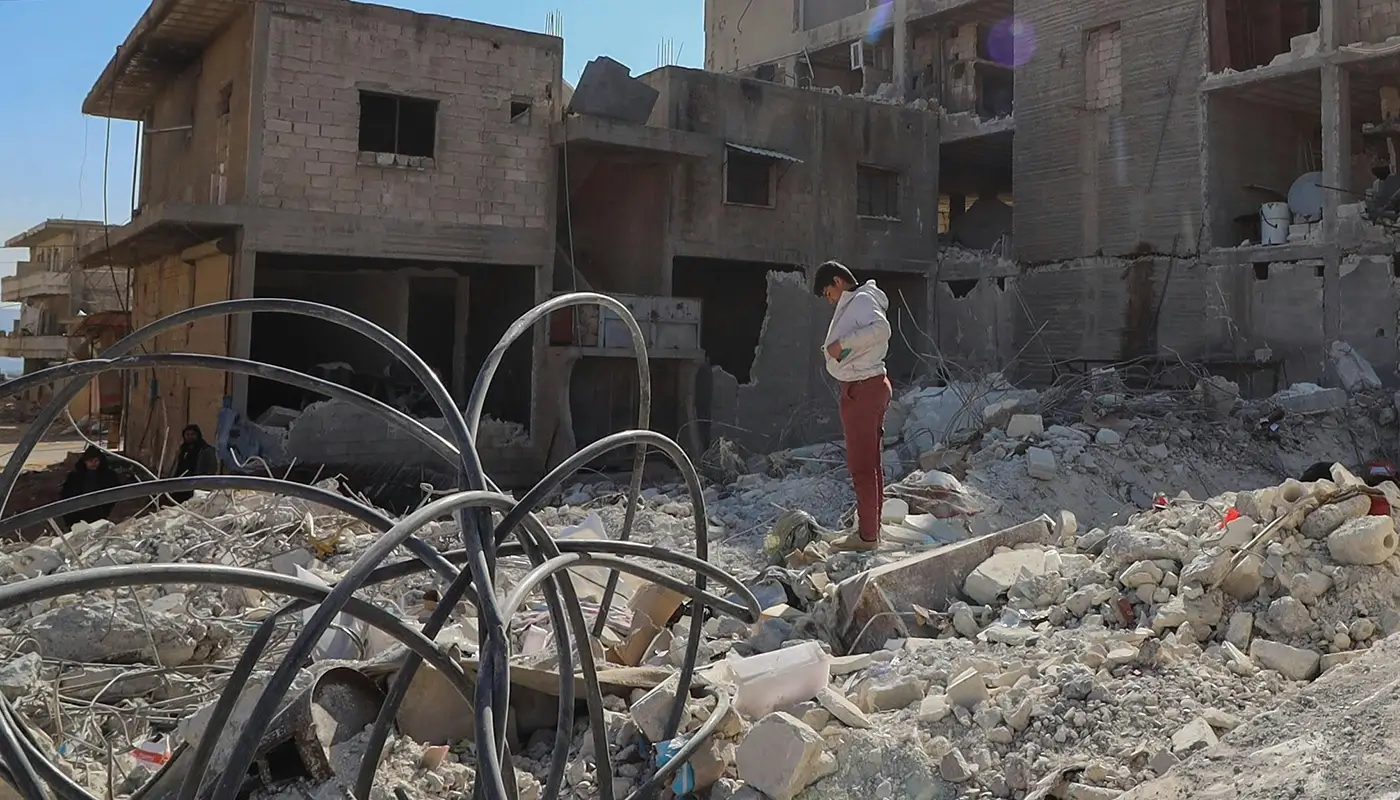 A man stands surrounded by the rubble of destroyed buildings in Lebanon.