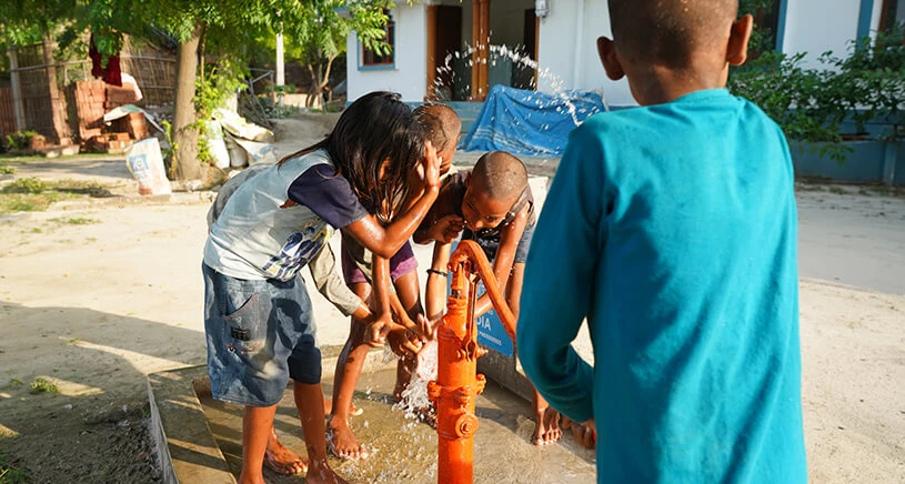 Children playing with clean water from well installed in their home thanks to Penny Appeal donors.
