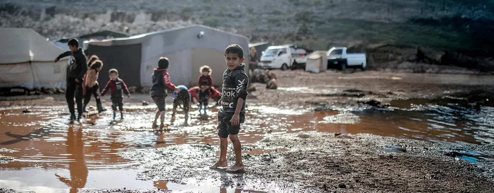 Children in a muddy displacement camp in Yemen, highlighting harsh conditions during the Penny Appeal Yemen Emergency response