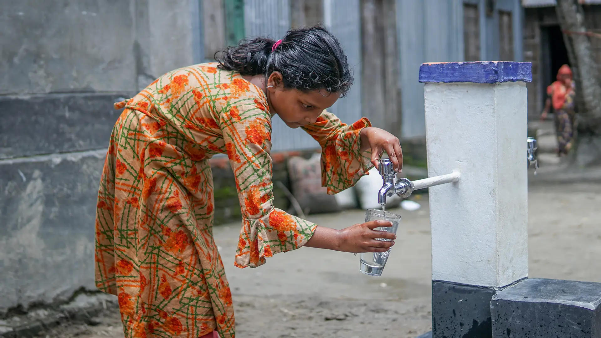 A young girl fills a glass with clean water from a tube well provided by Penny Appeal’s Thirst Relief project.